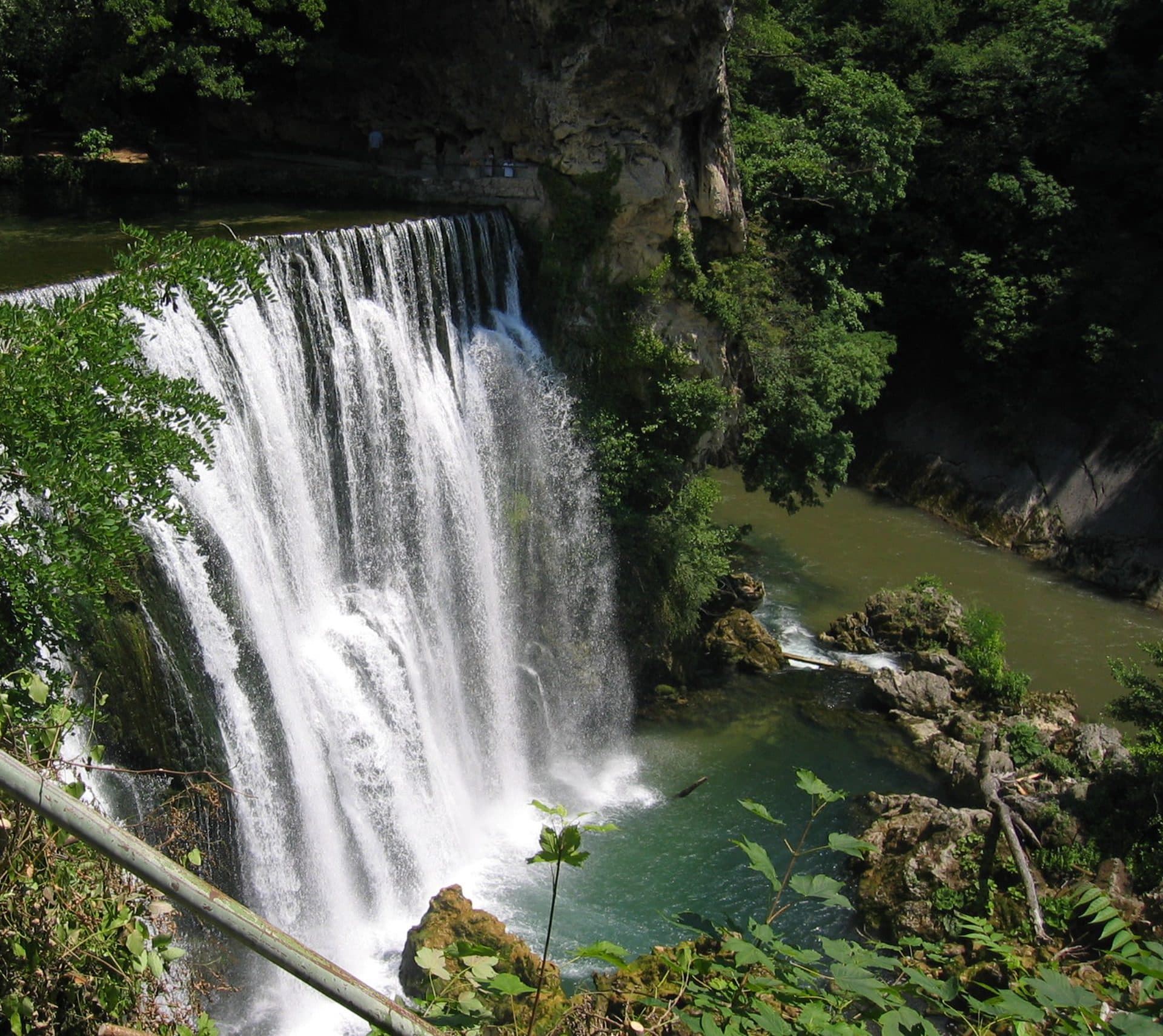 The Pliva waterfall dropping twenty-two metres into the Vrbas at the heart of Jajce, framed by summer greenery