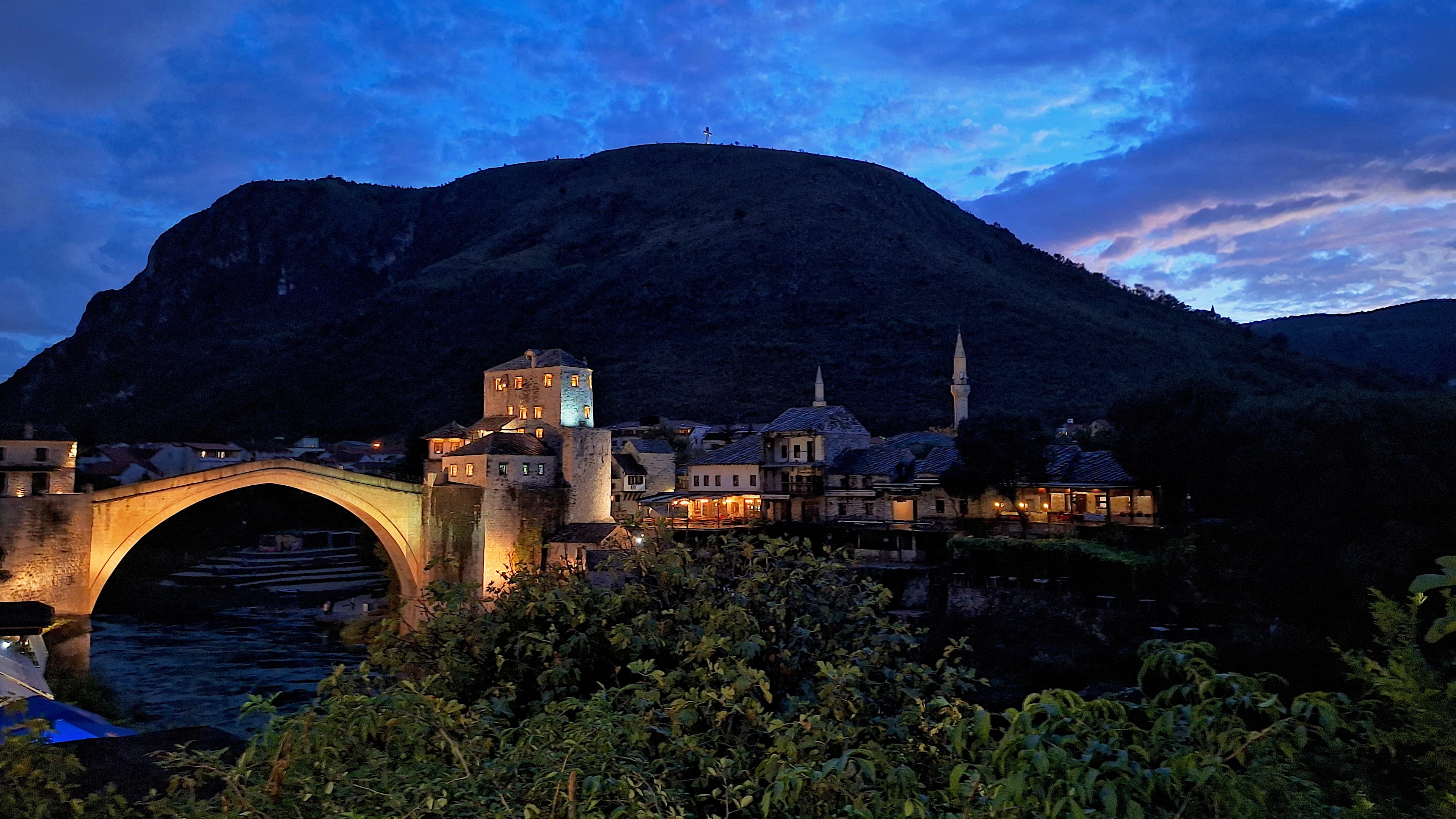 Mostar's Old Bridge arcing over the green Neretva at dusk